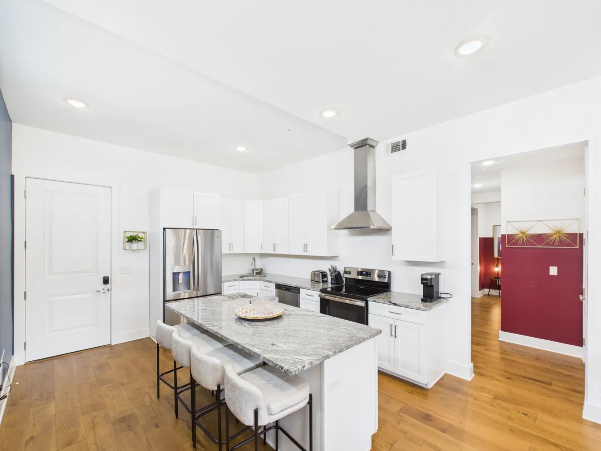 A warm, welcoming kitchen scene with a prominent island, stainless steel appliances, and a granite countertop. The atmosphere is set for lively cooking sessions, entertaining, and family gatherings, making it a focal point for group activities and shared moments.