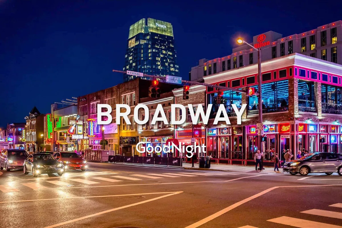 A bustling city street at night illuminated by vibrant neon signs, with people walking, traffic lights glowing, and a row of buildings that hint at lively bars, music venues, and eateries. The energetic street scene evokes the heart of Nashville’s nightlife and live music culture.