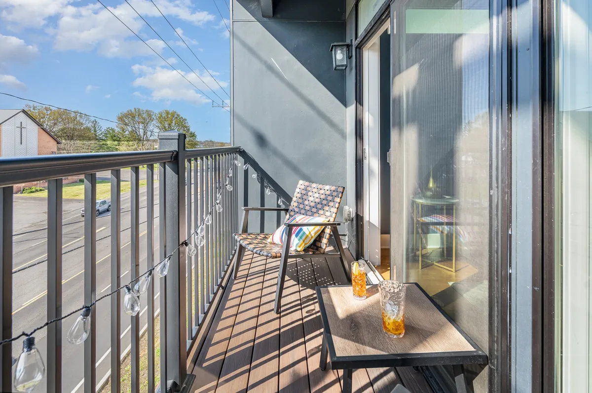 An inviting outdoor balcony scene featuring a cozy set of furniture, drinks on the table, and string lights overhead. The image exudes a relaxed, social vibe, perfect for enjoying sunsets, family gatherings, or winding down after a busy day of local adventures.