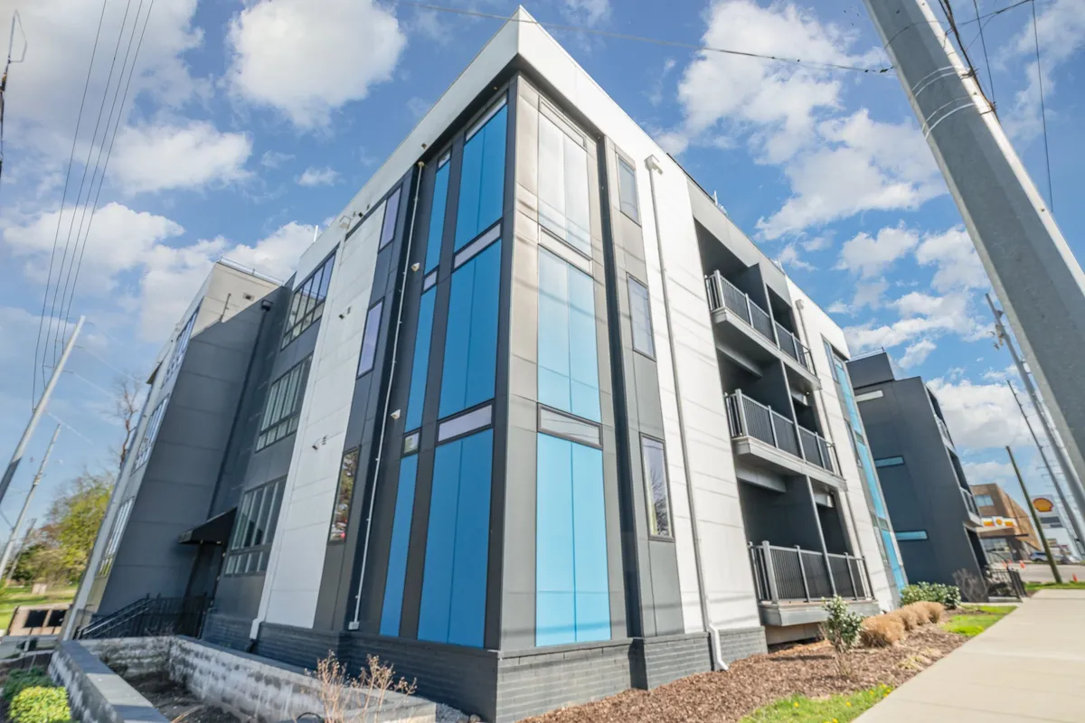 This image showcases the modern exterior of a residential building with striking blue and gray color tones and balconies, representing a vibrant city lifestyle. The architecture is contemporary and the presence of balconies alludes to private outdoor spaces for residents.